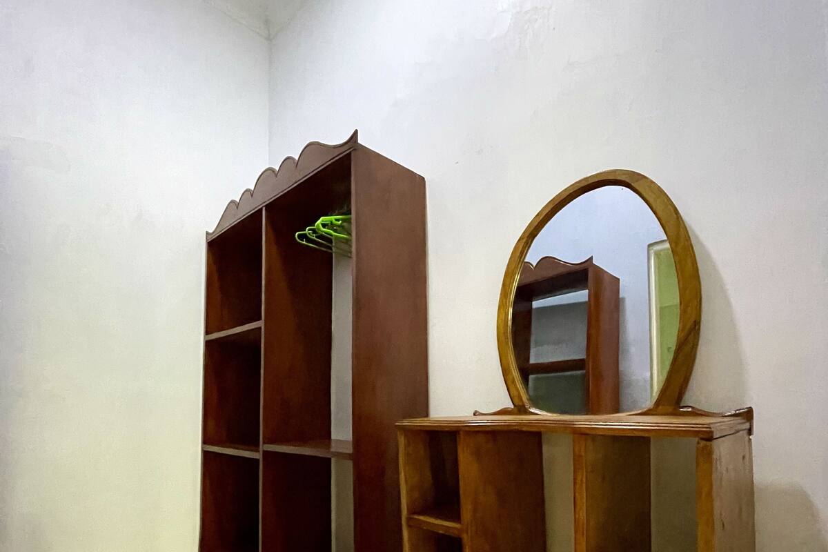 A room with a tiled floor, a wooden bookshelf, and a mirror on a stand.