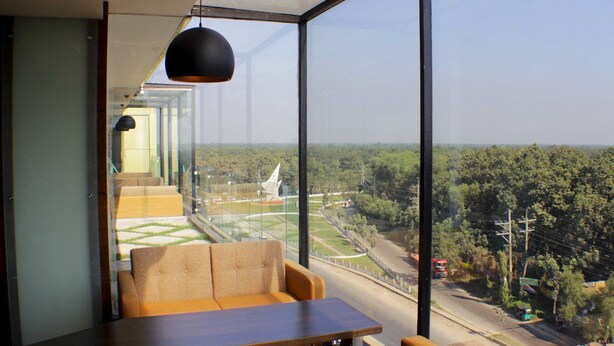 Un intérieur moderne doté d’une grande baie vitrée donnant sur un paysage verdoyant et une structure blanche.