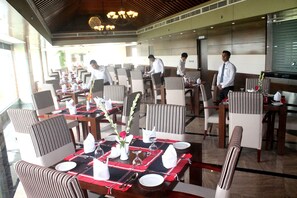 A restaurant with tables set for dining, staff attending to guests, and a modern interior design. - Hotel X (Pirozali)