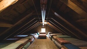 An attic bedroom with wooden beams, a sloped ceiling, and a central light fixture. - Rifugio Mulaz (Falcade)