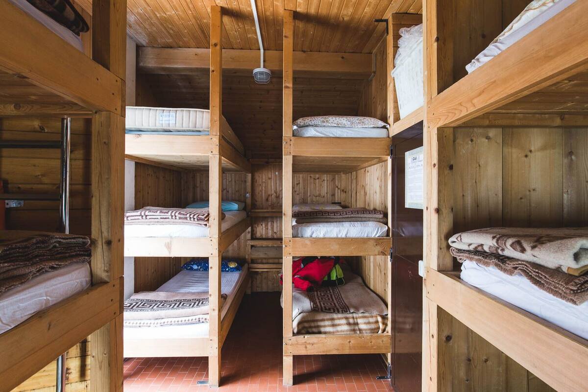 Una cabaña de madera con literas dispuestas en un pasillo central.