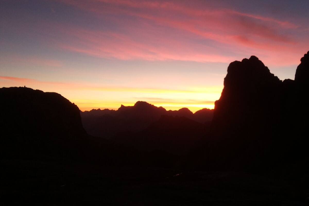 Silueta de un paisaje montañoso al atardecer con cielo despejado.