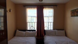 Ein Zimmer mit zwei Betten, einem Vorhangfenster und einer Wandleuchte.