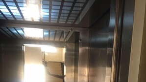Ein Aufzuginnenraum aus Metall mit einer reflektierenden Oberfläche und sichtbarem Türwerk.