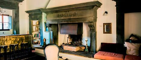 A traditional living room with a fireplace, a sofa, a chair, and a bar area with stools.
