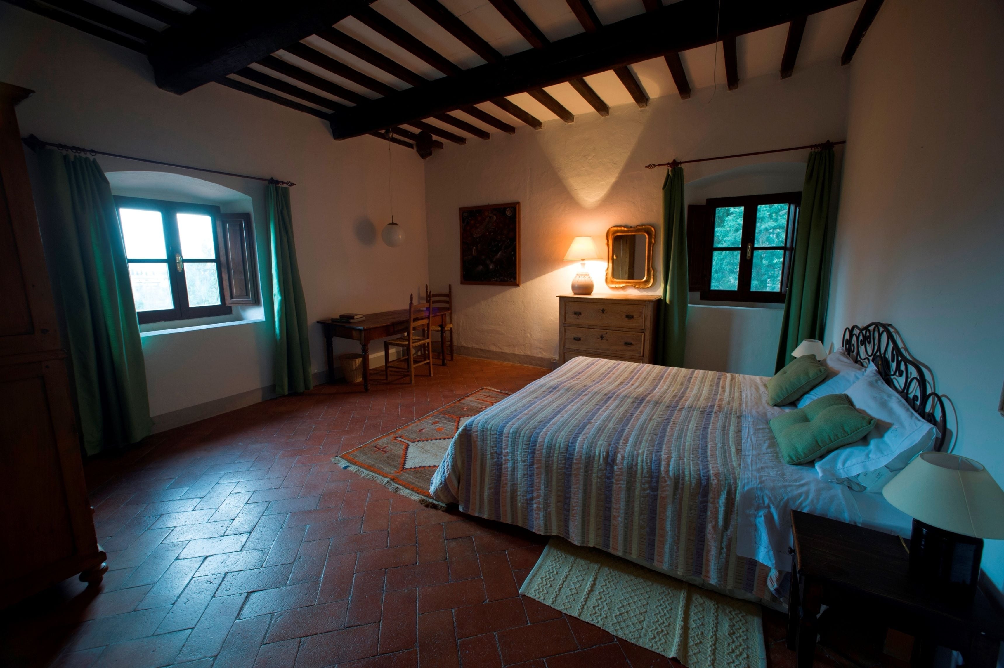 A bedroom with a bed, a dresser, a chair, and a window with curtains.