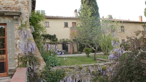 A stone building with a garden, including a pergola with purple flowers. - Il Poggio B&B (Scandicci)