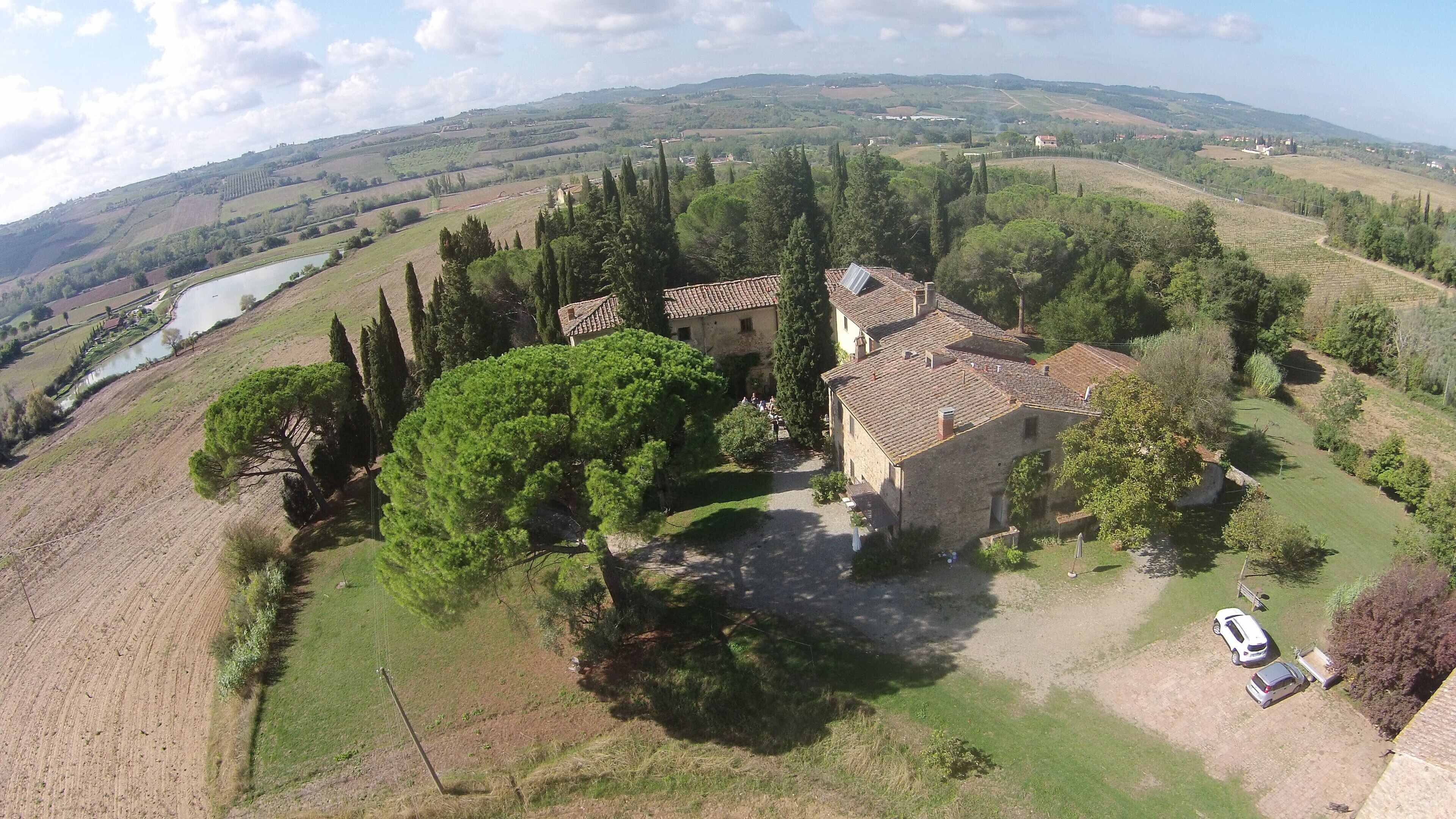 Una finca rural con un edificio de piedra rodeada de árboles y campos.