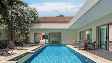 A modern pool area with lounge chairs and a stone wall.