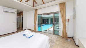 A hotel room with a bed, a ceiling fan, an air conditioning unit, a view of a swimming pool through glass doors, and a large window with curtains.