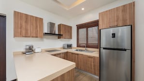 A modern kitchen with wooden cabinets, a stainless steel refrigerator, a microwave, and a coffee maker.