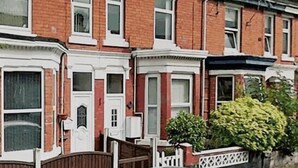 A row of terraced houses with a white picket fence, a car parked in front, and a small bush to the right. - Walthall Place (Crewe)