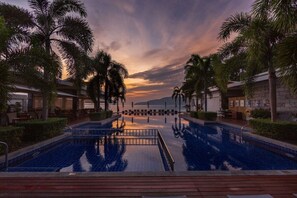 Una piscina al aire libre, sombrillas, sillones reclinables de piscina