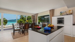 A modern kitchen with a central island, large windows, and a view of the sea. - Serenity Grand Seaview Suite (Rawai)