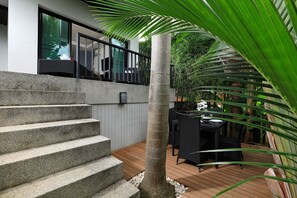 A modern outdoor staircase leading to a balcony with a wooden deck and outdoor furniture. - Villa Emauha (Rawai)