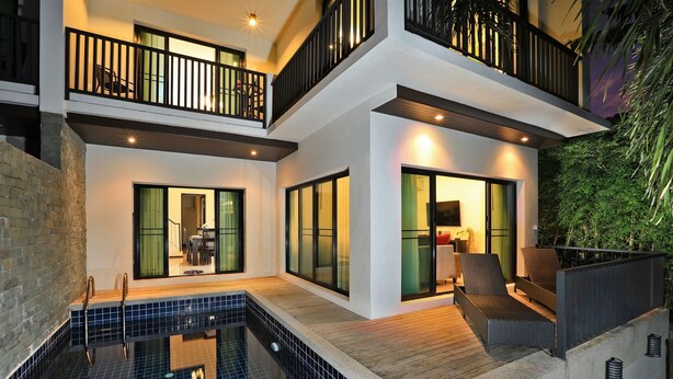 Une maison moderne à deux étages dotée d’une piscine, d’un espace salon extérieur et d’un balcon.
