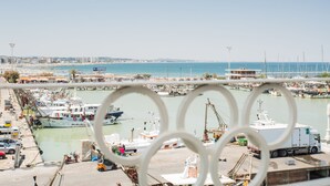 Un puerto deportivo con barcos amarrados, un camión y una estatua al fondo.