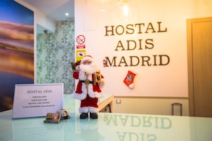 Una reception con la targa dell'Hostal Adis Madrid, che indica gli orari di check-in e check-out, i dettagli del WiFi e la password.