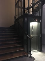 Una scala conduce a un ascensore con un display digitale.