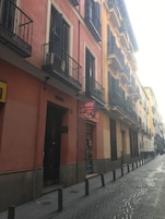 Una strada con edifici dotati di balconi e una vetrina con un cartello.