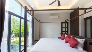 Een moderne hotelkamer met een groot bed, een plafondventilator en uitzicht op groen.
