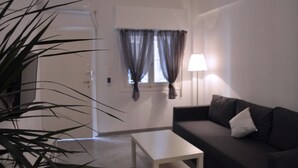 Un salon avec un canapé de couleur foncée, une table basse blanche et une lampe.