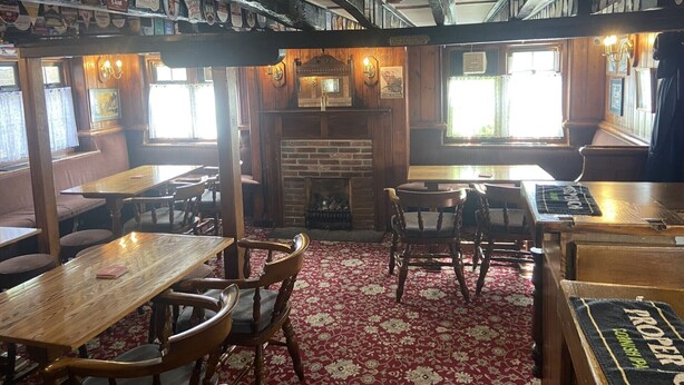 A pub with wooden furniture, a brick fireplace, and a red carpeted floor. - The Jolly Drayman Pub and Hotel (Gravesend)