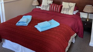 A neatly made bed with a red and white bedspread, two folded towels, and a chandelier above. - The Jolly Drayman Pub and Hotel (Gravesend)