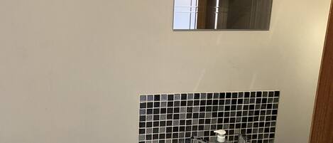 A bathroom with a white sink, a mirror above it, and a black and white tiled backsplash.