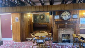 A pub with wooden walls, a dartboard, a clock, and a fireplace. - The Jolly Drayman Pub and Hotel (Gravesend)