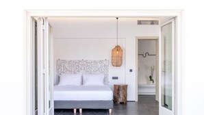 Un dormitorio moderno con una cama, una lámpara colgante y un taburete de madera.