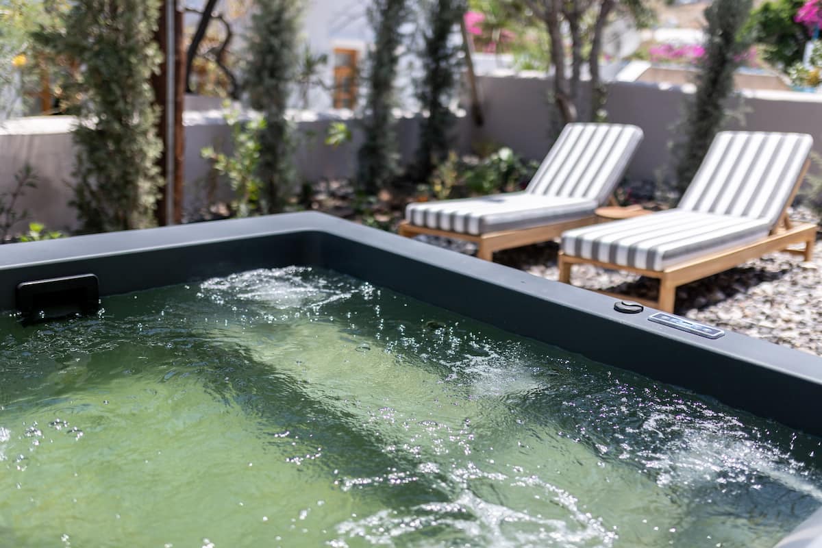 A hot tub with two lounge chairs in a garden setting.