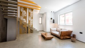 Una sala moderna con una mesa de centro de madera, un sofá y una escalera con un panel decorativo geométrico.
