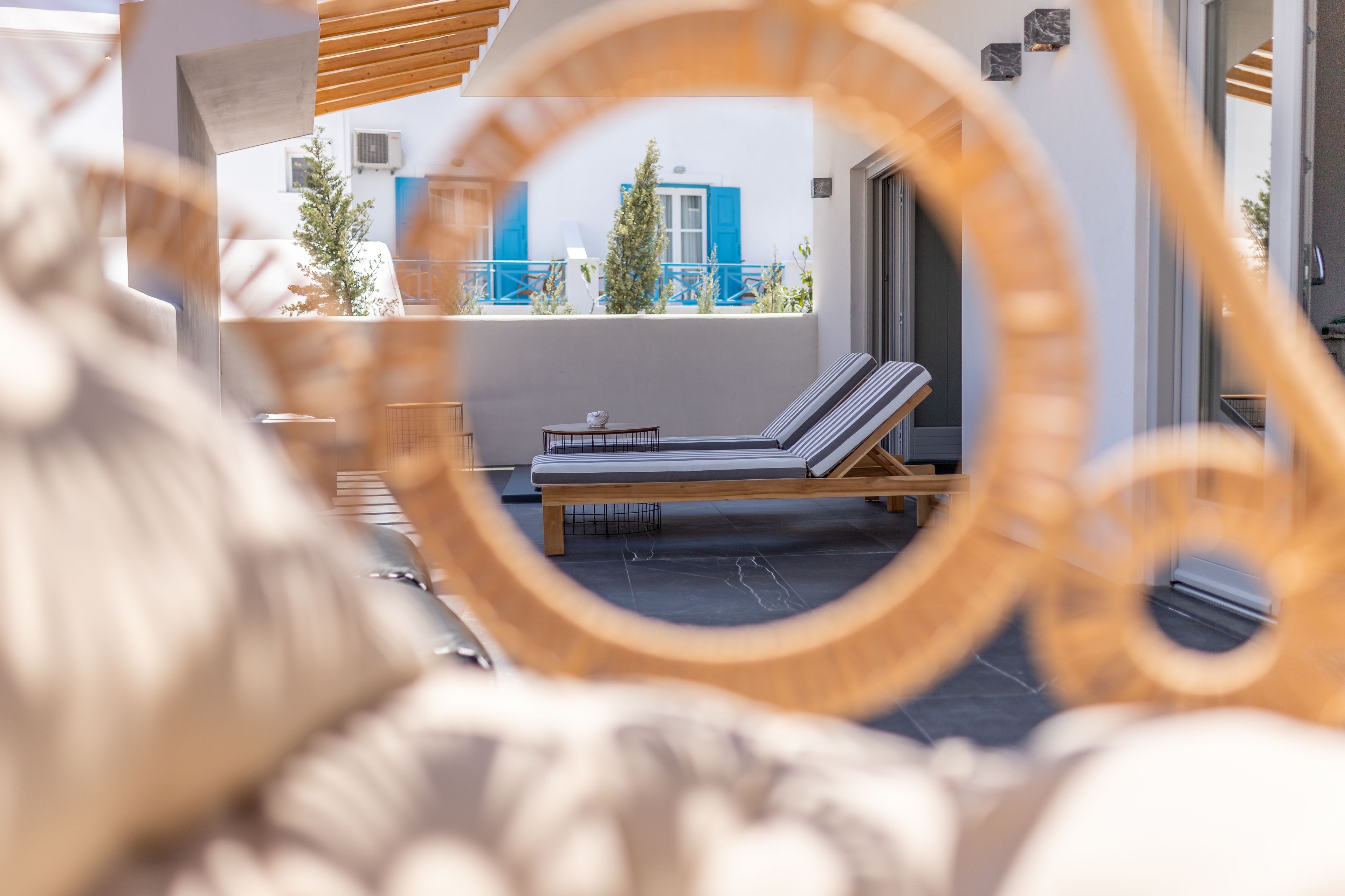 A sun lounger on a balcony with a view of a building with blue shutters.