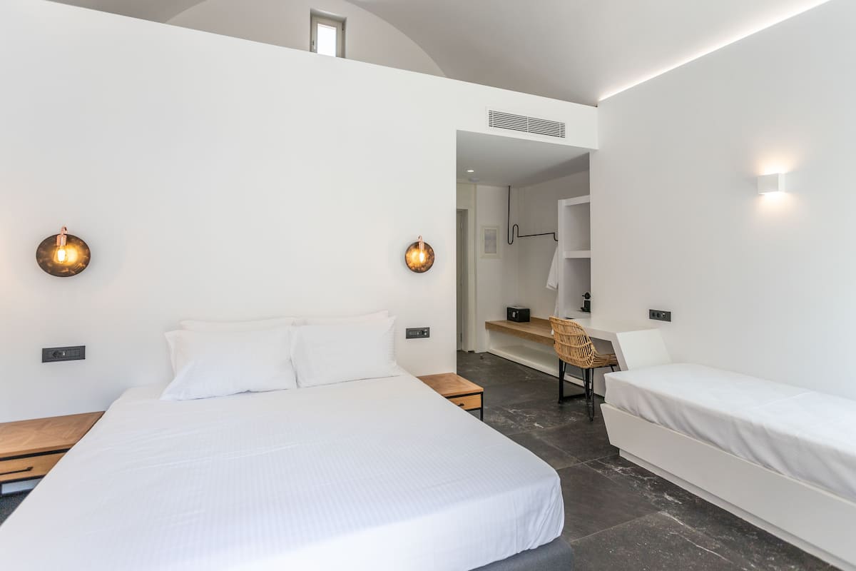 A modern hotel room with a large bed, a desk, and a chair.