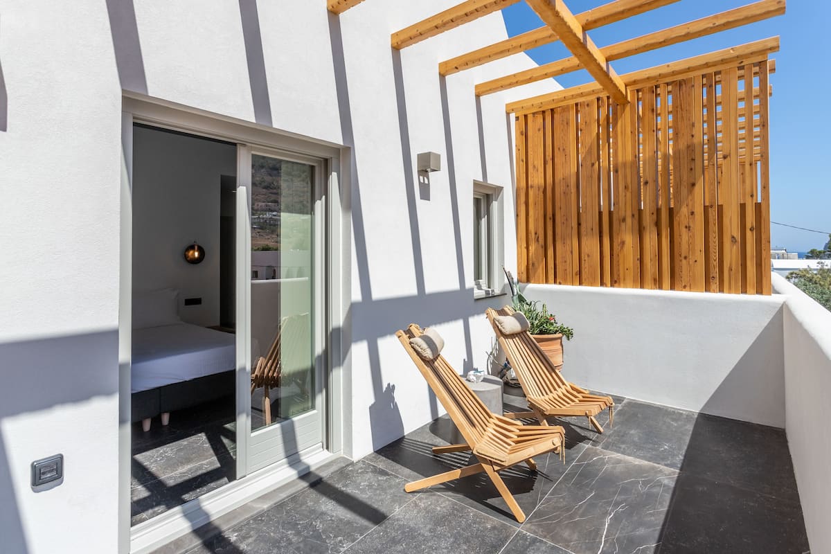 A balcony with two wooden lounge chairs, a small table, and a potted plant.