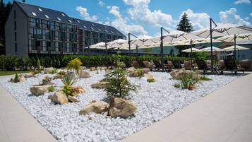 A modern outdoor seating area with white pebbles and rocks, surrounded by lounge chairs and umbrellas.