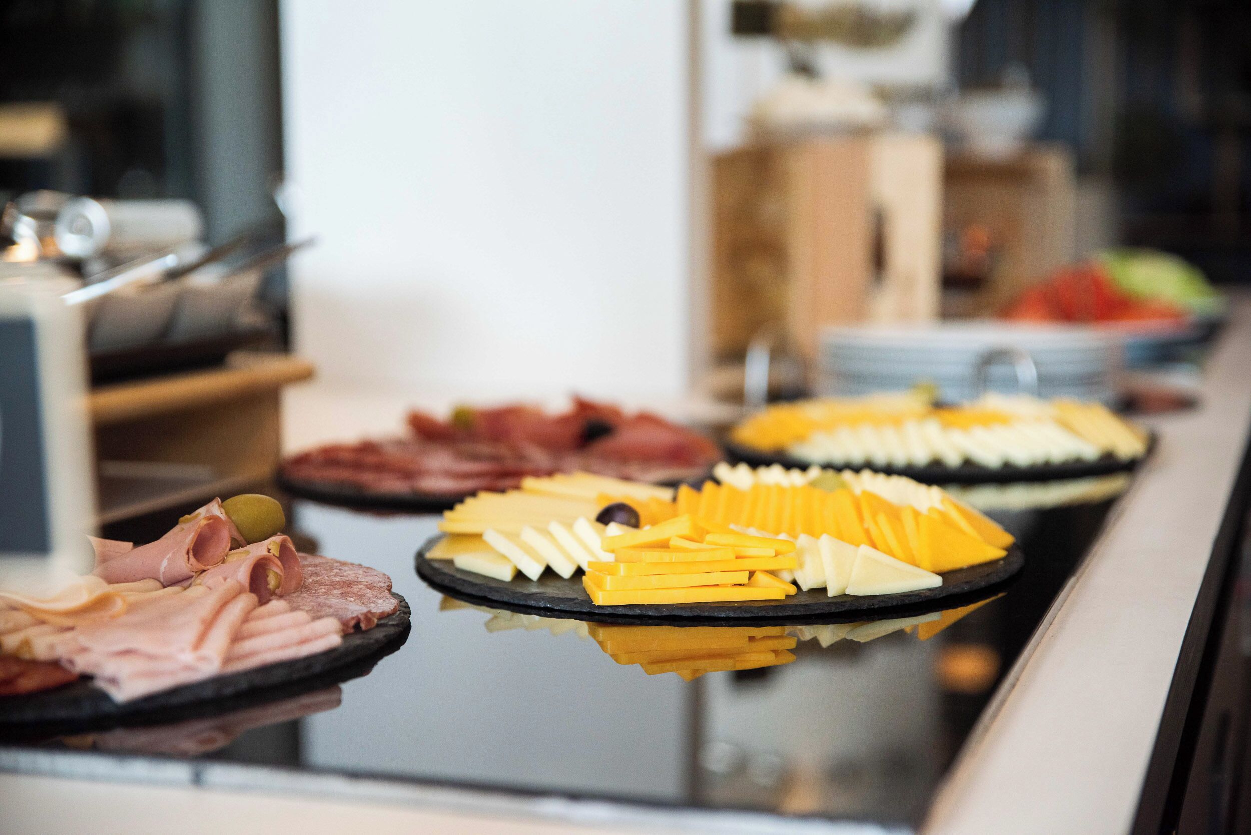 A buffet with various food items including meats, cheeses, and fruits.
