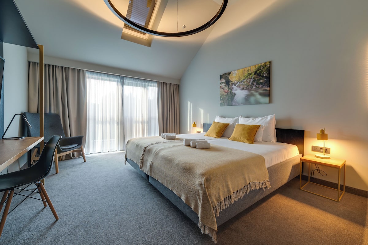 Una habitación de hotel moderna con una cama grande, un escritorio y una silla.