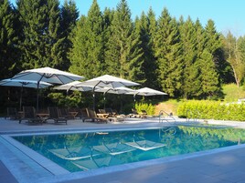 Una piscina al aire libre de temporada, sombrillas