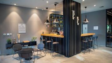 A modern bar area with a wooden counter, bar stools, and pendant lighting.