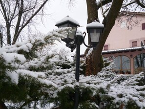A snow-covered street lamp and trees in a residential area. - B&B Four Winds (Follina)