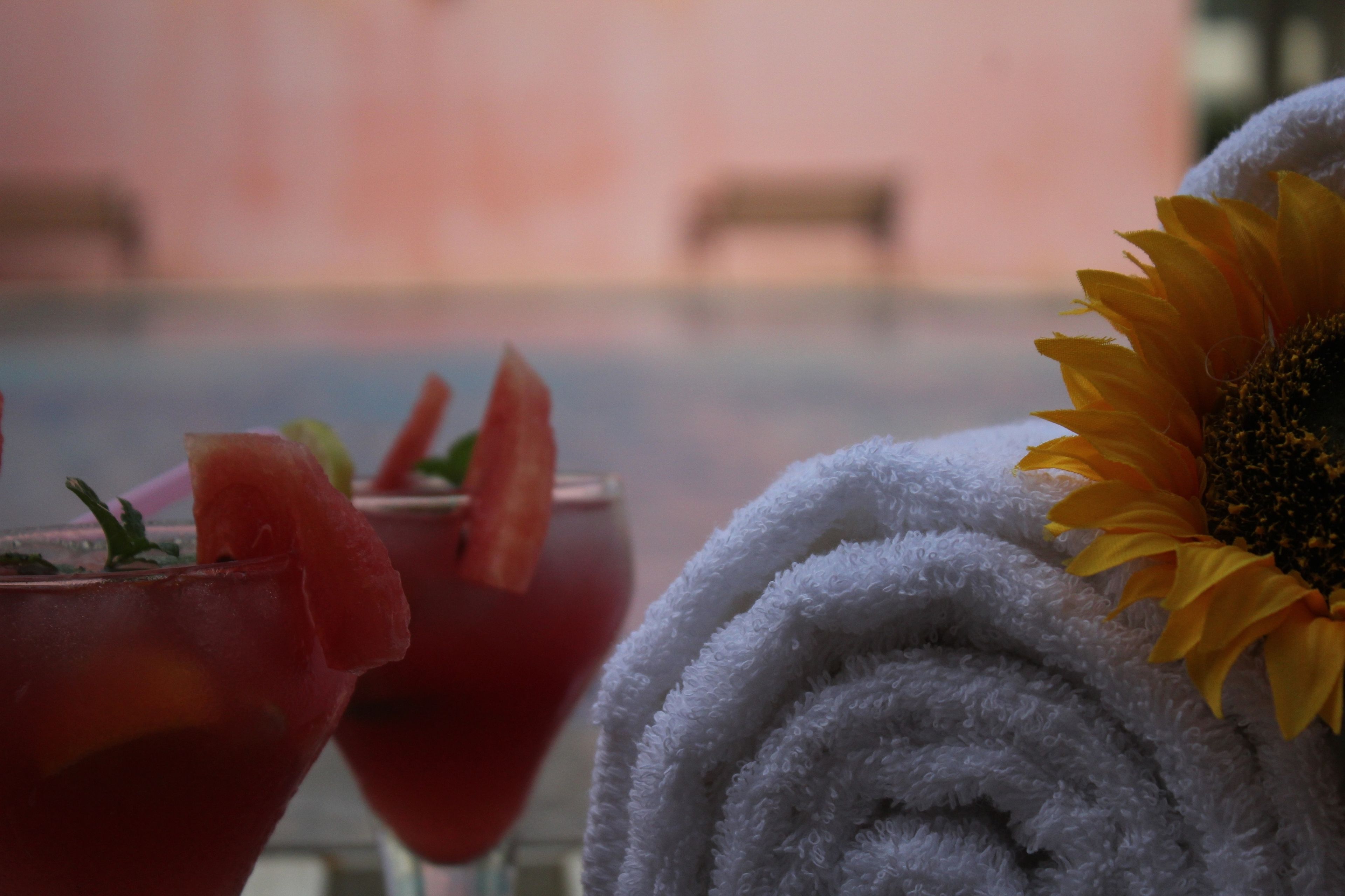 Un asciugamano con un girasole e due bevande guarnite con frutta.