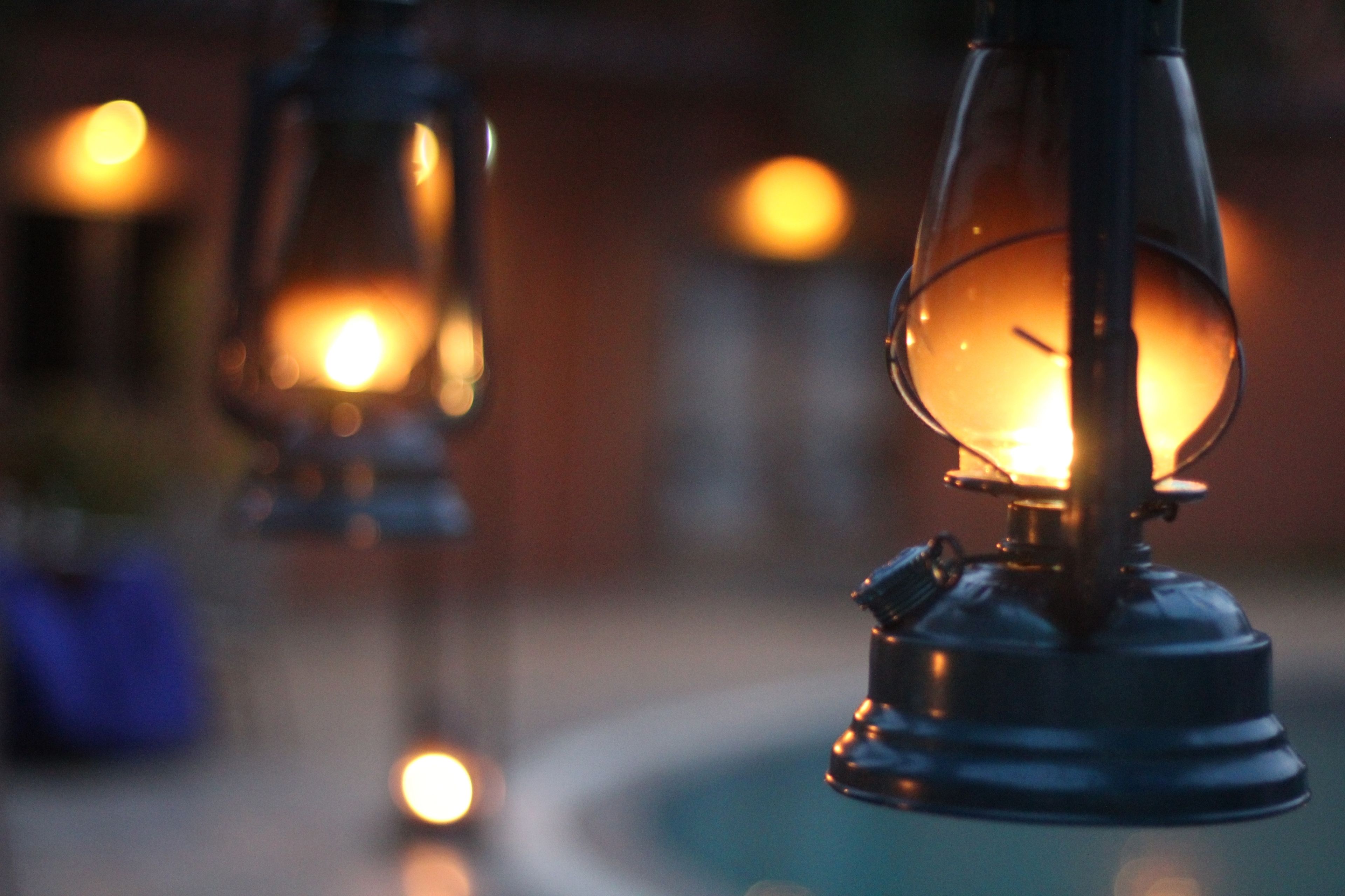 A close-up of a lantern with a glowing light source, possibly a candle or bulb, inside a glass enclosure.