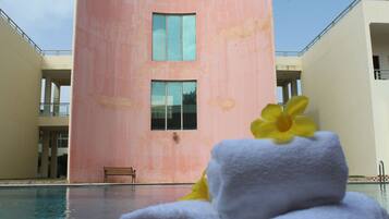 Ein pinkfarbenes Gebäude mit Pool, einer Bank und einer Blume auf einem Handtuch.