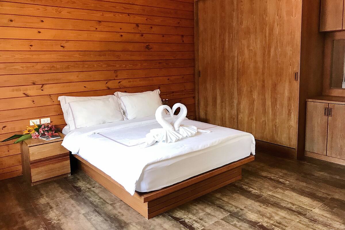 Una habitación con paneles de madera, una cama, una mesita de noche y un armario.