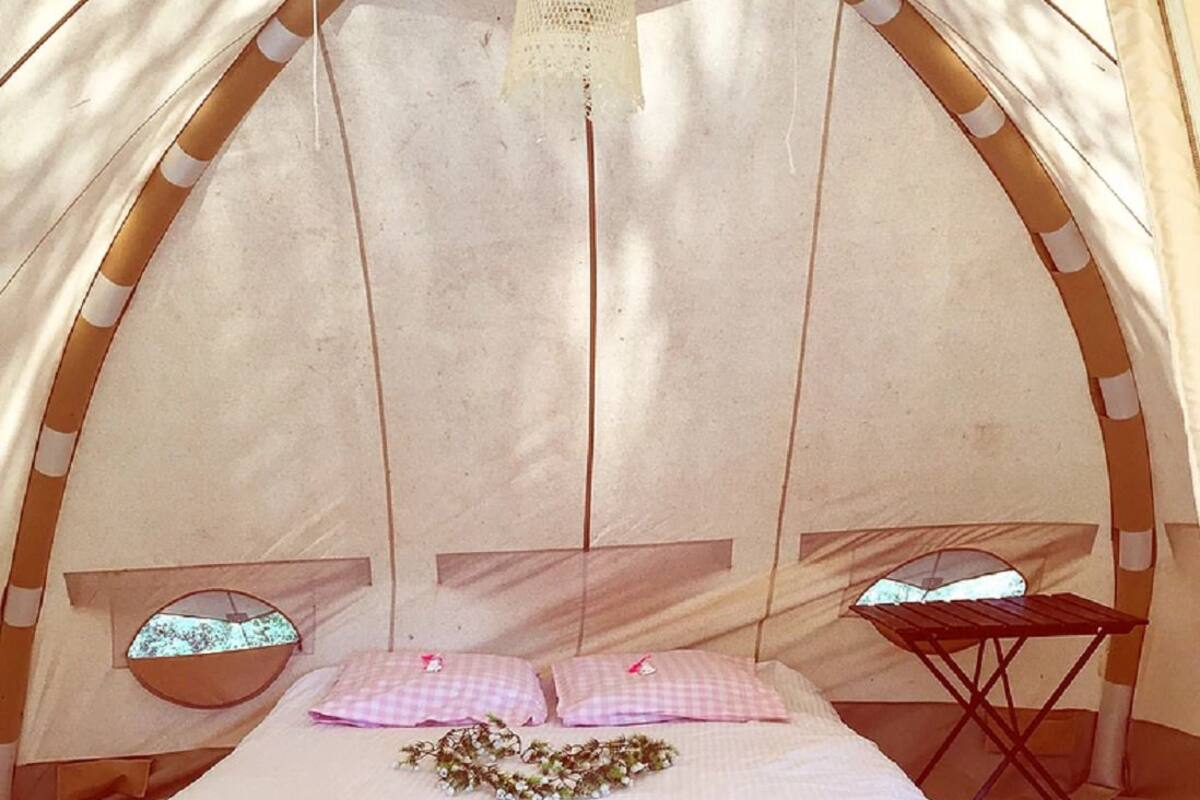 Une tente équipée d’un lit, d’une petite table et d’une fenêtre.