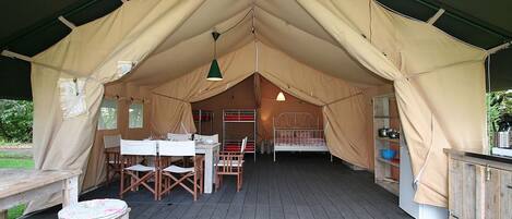 Une tente comprenant un espace repas, un lit et un coin cuisine.