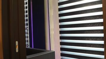 Un interior moderno con una escalera que baja a un nivel inferior, una pared con persianas horizontales y un marco de puerta visible.