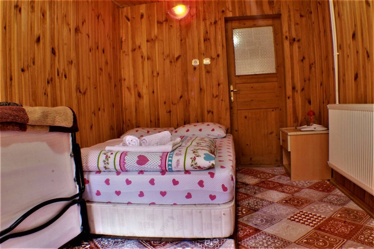 Una habitación con paneles de madera, una cama, una mesita de noche y un radiador.